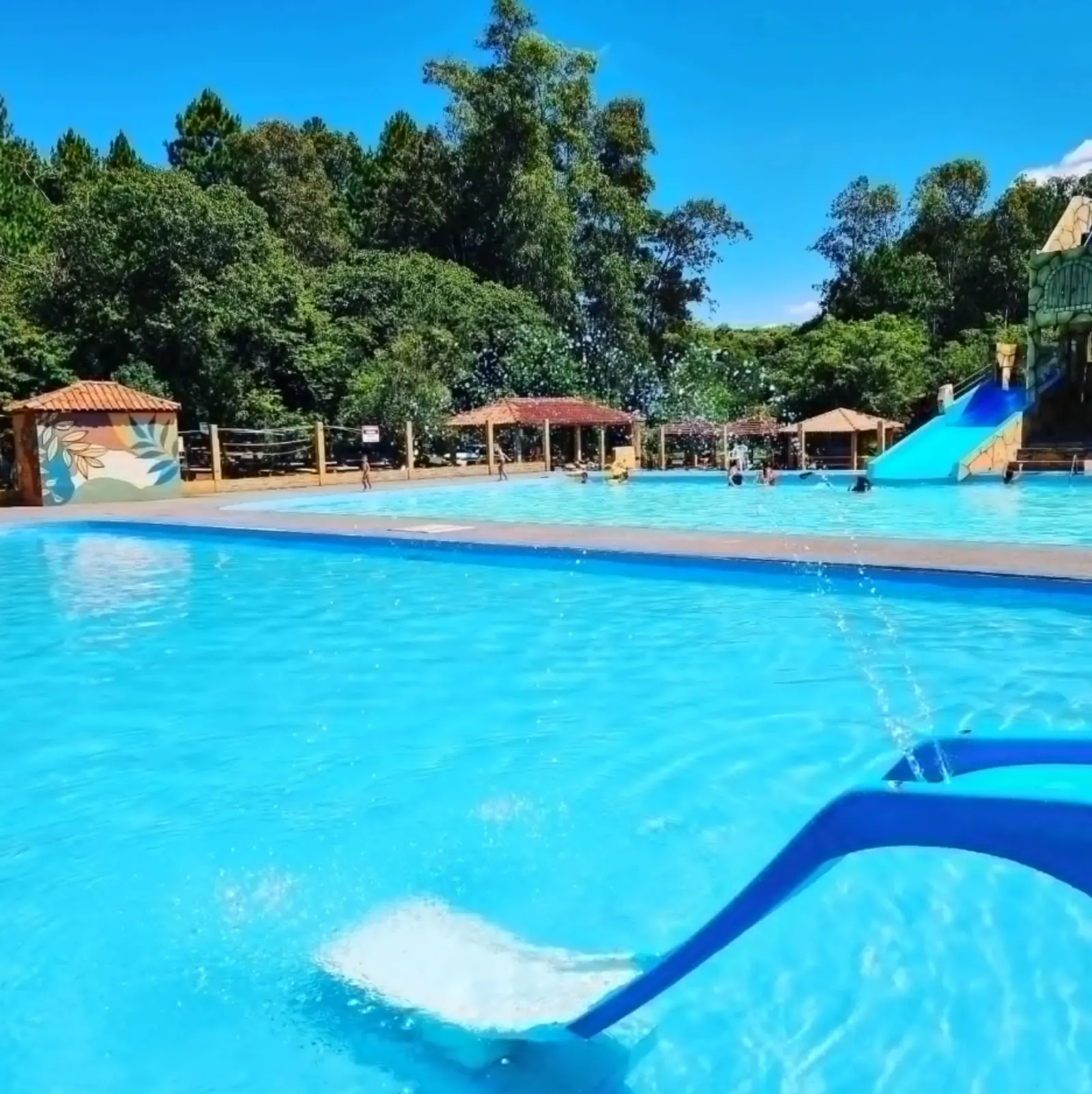 Área principal da piscina com espreguiçadeiras e guarda-sóis