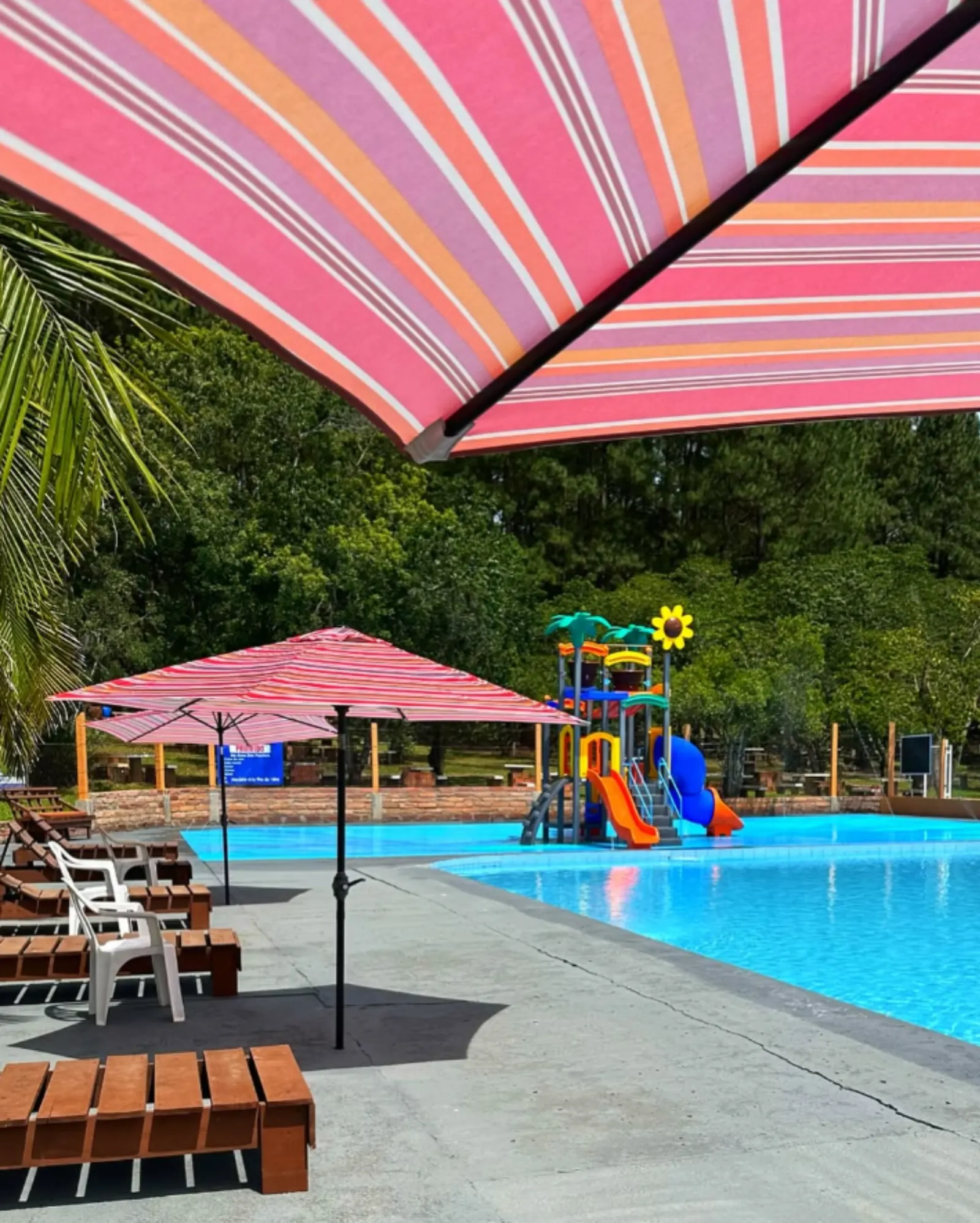 Piscina infantil com escorregador e guarda-sóis coloridos